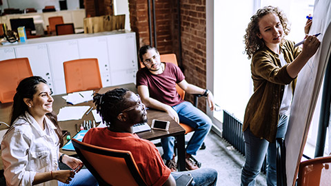 woman writing while on meeting on colleague