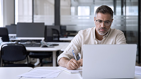 Businessman busy working with laptop while taking notes