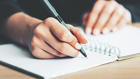 A close view of a person writing a meeting agenda