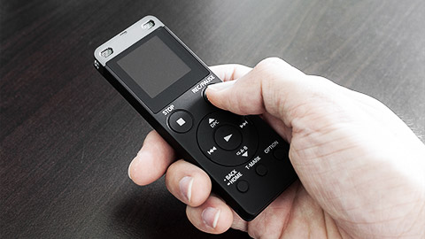 A voice recorder being held by hand