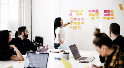 A group of employees writing procedures on a glass board