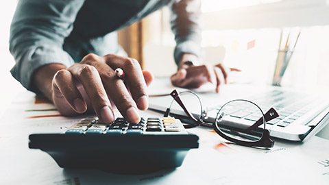 A close view of the hand of an accountant typing numbers on a calculator