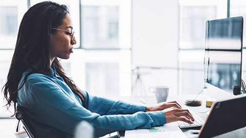 Side view of an accountant sitting at a desk working on a desktop computer