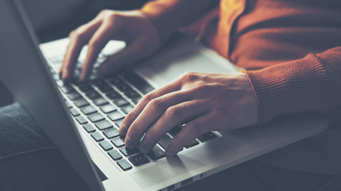 A close view of a person typing info on a laptop