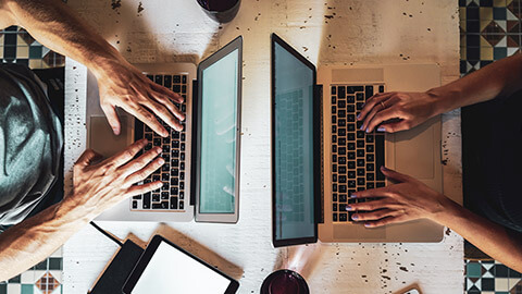 Top down view of 2 people doing accounting work on laptops