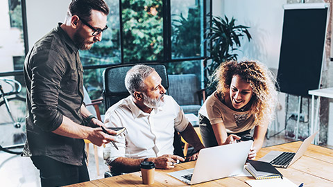 A group of accountants standing at a table discussing formulas