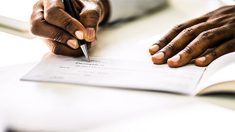 A Financial Controller signing a cheque on behalf of their organisation