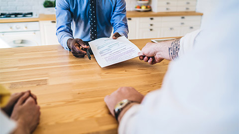 A solicitor handing their client a contract to execute