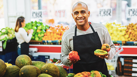 A grocery store owner inspecting fruit in a store