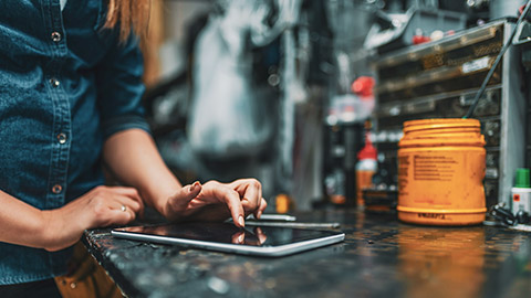 A close view of a bicycle mechanic entering accounting information on a tablet, resting on a counter top