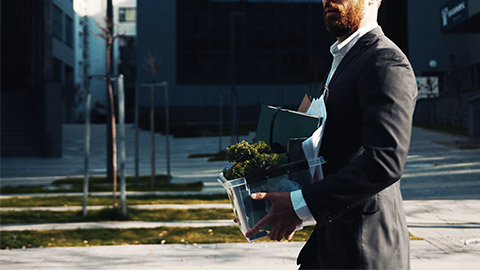 An employee walking out with personal belongings in hand