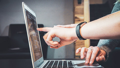 A close view of a hand pointing to information on a computer screen