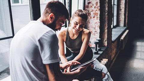 2 fitness instructors looking at information on a tablet device