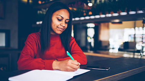 A business owner writing a report on a notepad