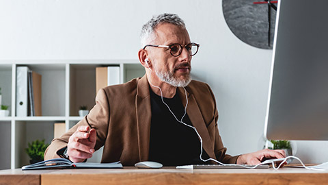 Business manager sitting at a desk in a modern office typing a document on a desktop computer