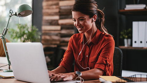 An employee sitting at a desk typing a business document on a laptop