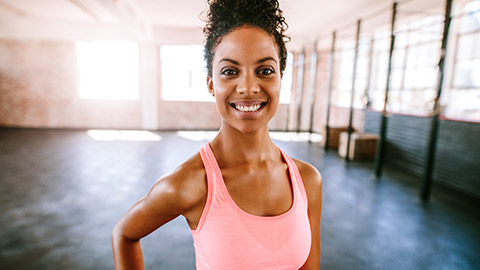 A smiling fitness instructor standing in an empty gym