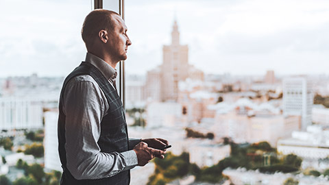 A business person feeling the stress of work-related issues looking out the window of an office