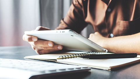 A close view of a business professional sitting at a desk looking at information on a tablet device