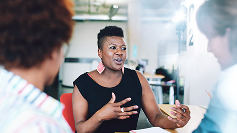 A female business professional in a discussion with 2 colleagues in an office