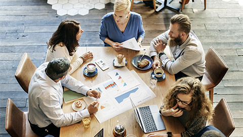 A group of professionals discussing data and graphs over coffee