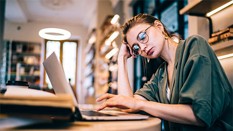 A professional seated at their desk and procrastinating, rather than focusing on the project they're responsible for