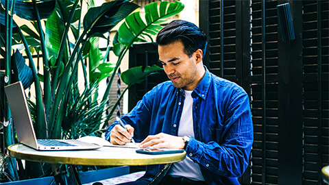 A professional working remotely, taking minutes during a meeting being held through a video call