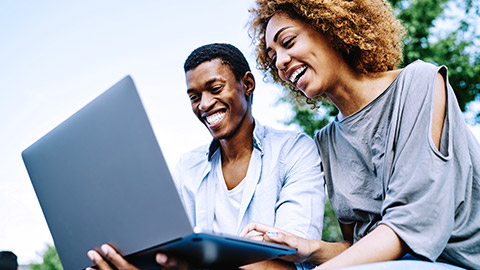 Man and woman happily having online conference with laptop