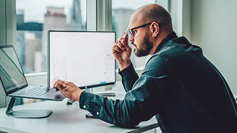 An accountant at a desk with data displayed on 2 computers