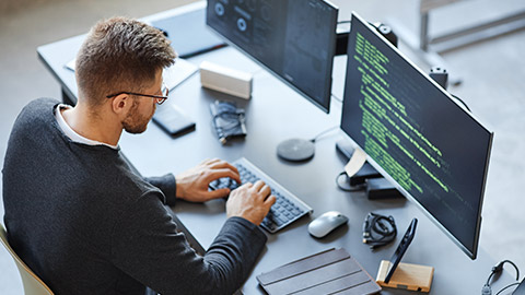 High angle view at software developer writing code while using computer and data systems in office