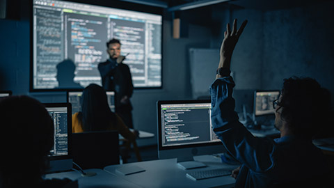 Teacher Giving Computer Science Lecture to Diverse Multiethnic Group of Female and Male Classmates in Dark College Room