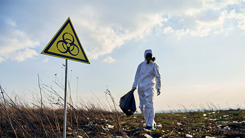 A person wearing the appopriate PPE, collecting biohazardous materials in wetlands