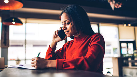 A receptionist taking down notes as they speak to the person on the other end of the phone call