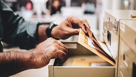 A close view of a person removing some records from their filing cabinet