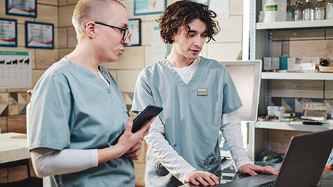 2 clinic workers discussing information on a laptop