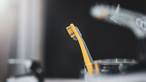 A close view of some toothbrushes sitting in a holder next to a sink