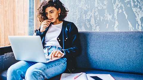 A student seated on a comfy sofa, working their way through an assessment