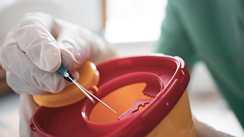 A vet disposing of sharps in a container