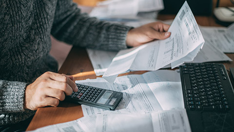 Close-up of male hands with a utility bill, a lot of checks and a calculator on the table