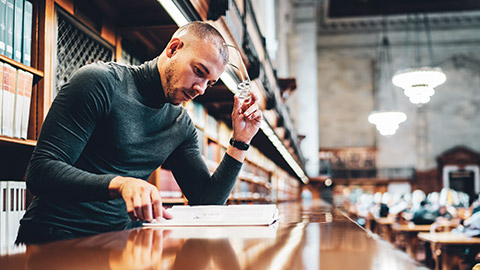 A hipster designer reading a book in a library