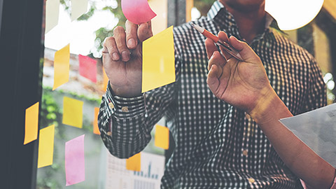 Close view of designers writing ideas on sticky notes