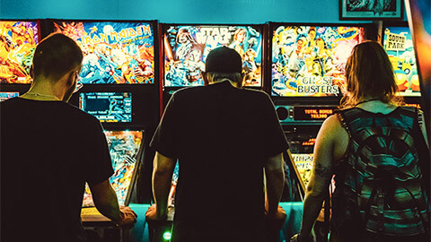 A group of friends playing pinball in a local arcade