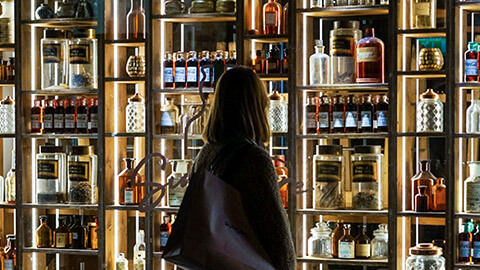 A person looking through a shop window with a wide variety of products visible