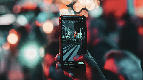 A close view of a person taking a picture on a phone in a busy city