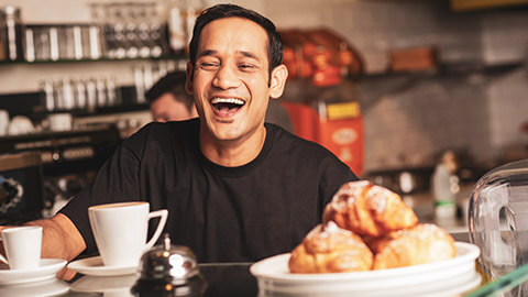 A smiling cafe owner serving a client