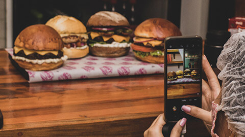 A creator taking a picture of some delicious burgers for a social media post