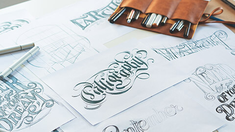 A close view of a typographers table with various letterforms drawn on paper