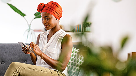 A user seated on their sofa, scrolling through content on their smart phone