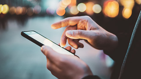 A close view of a person interacting with an app on their phone on a street