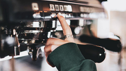 A close view o f afinger pushing a button on a coffee machine